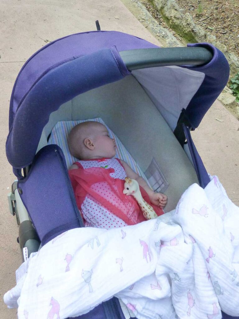 a baby from the BabyCanTravel family sleeps soundly in a stroller while on a family vacation in Europe..