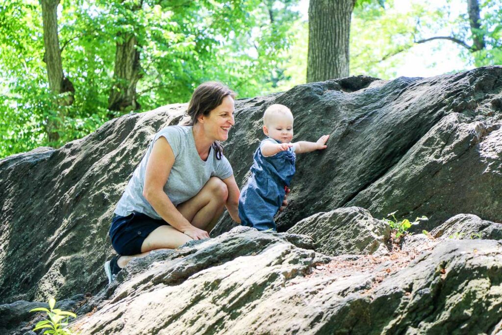 a mom plays with her baby in Central Park while on a family trip to New York City.