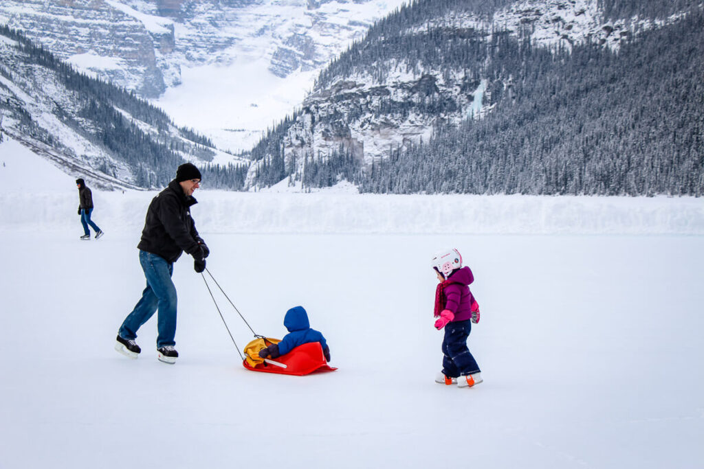 a family having a great time skating on Lake Louise in winter with baby and toddler.