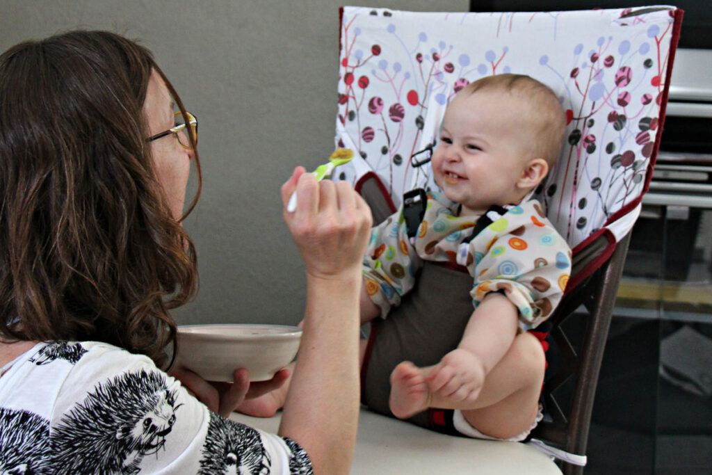 baby in travel high chair being fed