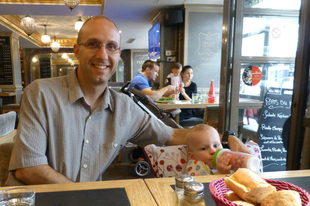 father and baby eating in restaurant with baby in portable fabric travel high chair