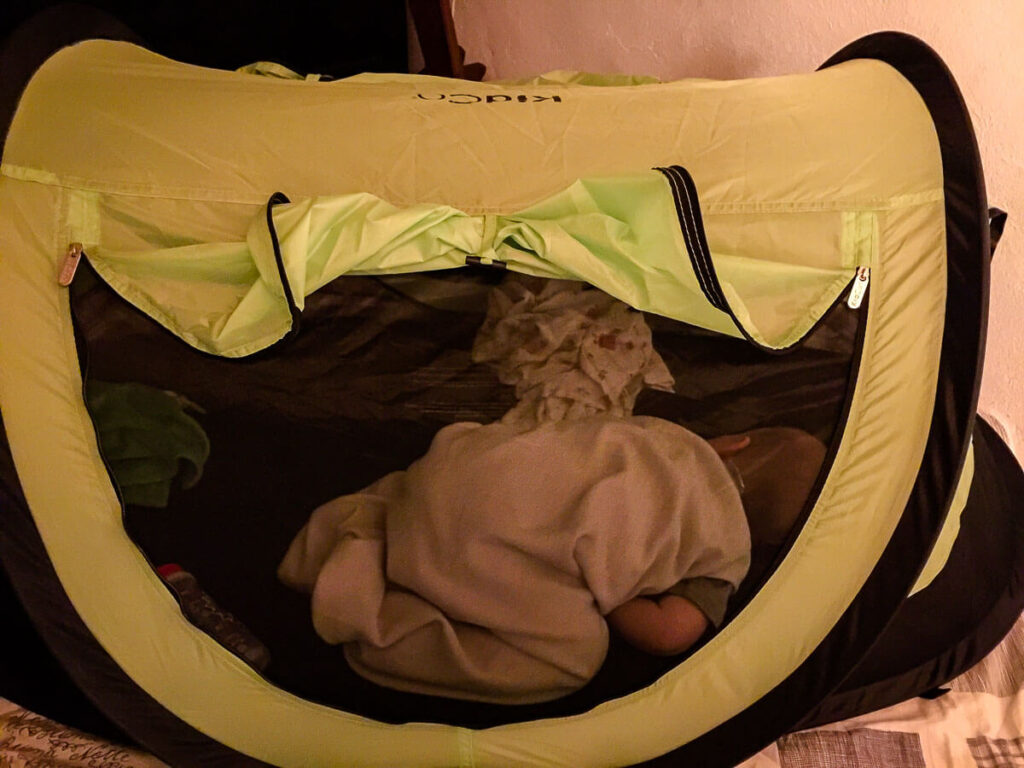 Toddler sleeping in KidCo PeaPod Plus tent while on a family vacation.