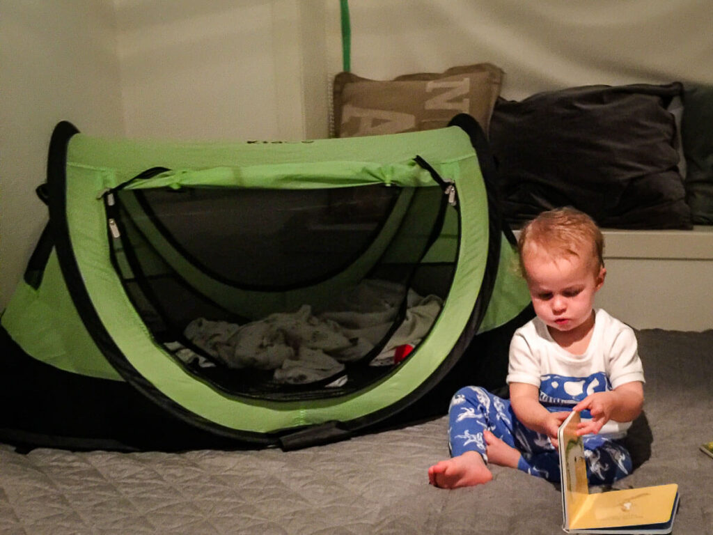 Toddler sitting beside kidco peapod tent.