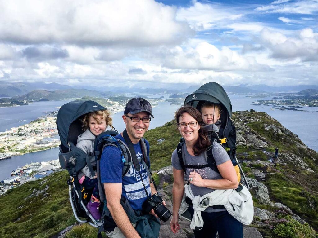 Celine Brewer and Dan Brewer, the people behind the BabyCanTravel.com website, carry their children in backpack carriers while hiking in Alesund, Norway.