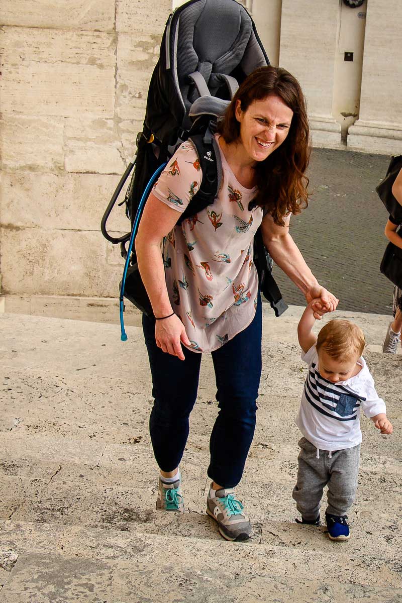 Celine Brewer, from BabyCanTravel.com, walks with her toddler in Rome, Italy while wearing a hiking backpack carrier.