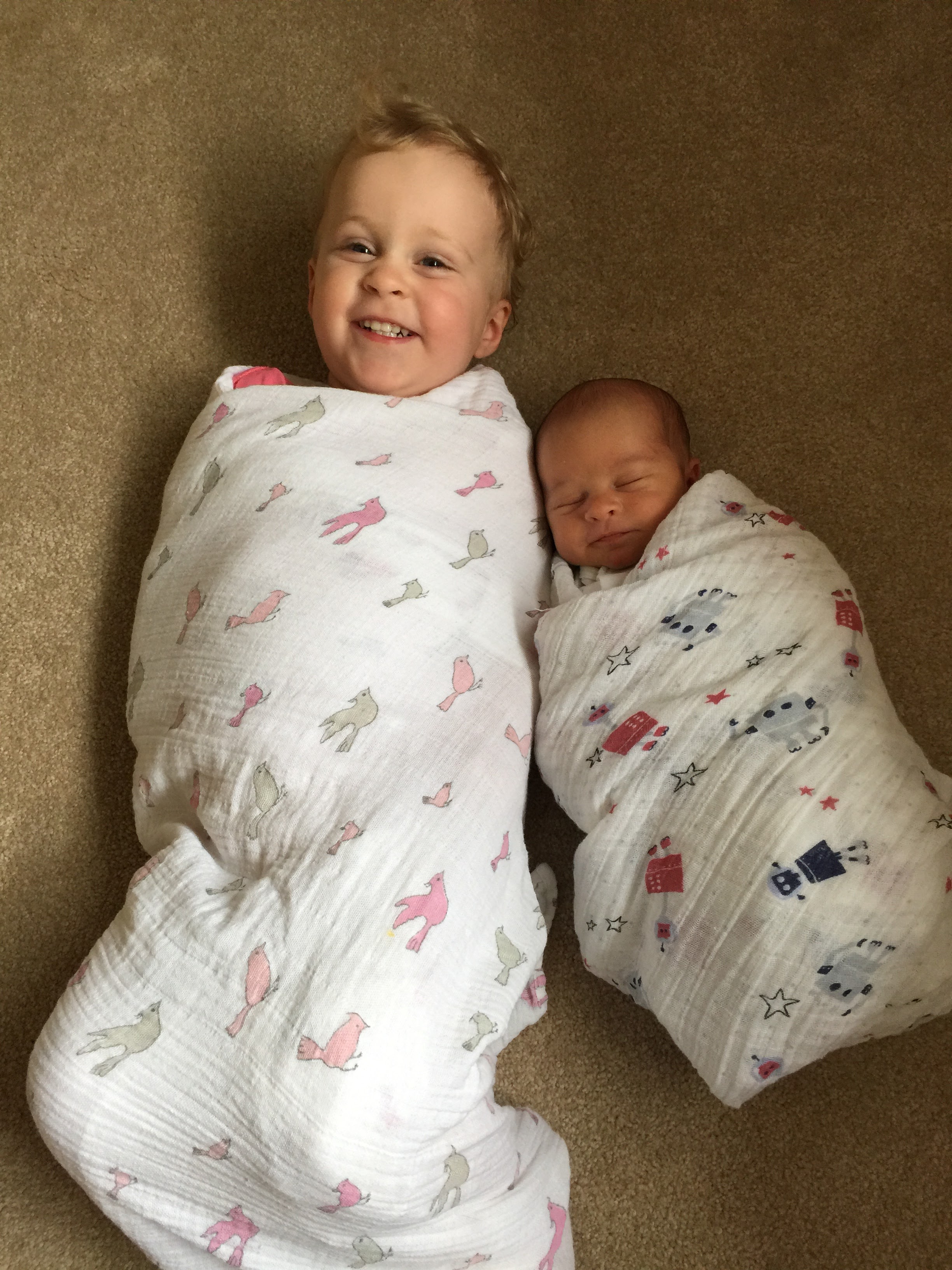 a toddler and a baby enjoying their Aden & Anais swaddle blankets.