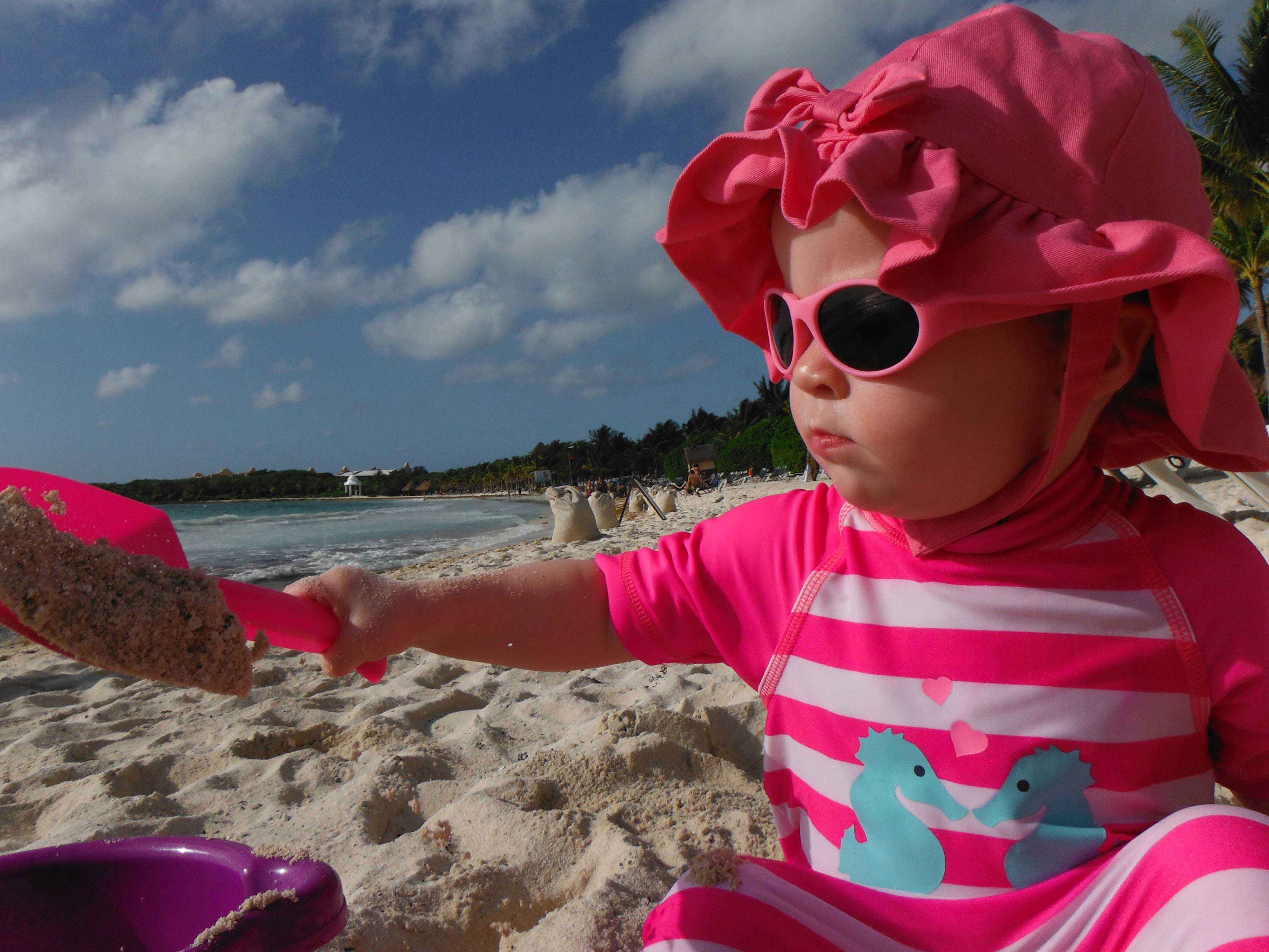 A baby girl plays with her beach toys at a family-friendly All-Inclusive resort in Mexico.