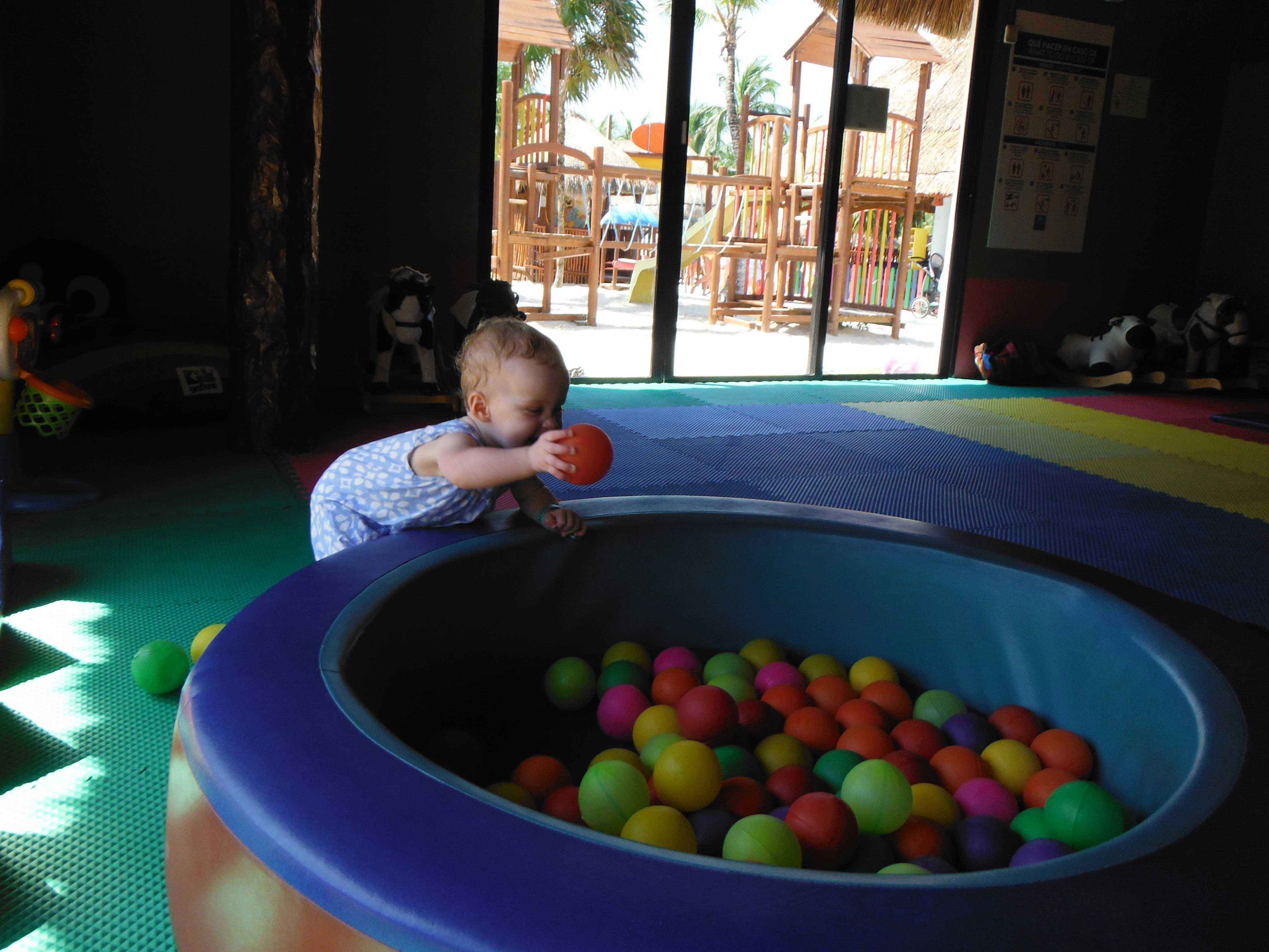 a baby plays with a ball pit at the kids club at her all-inclusive resort.