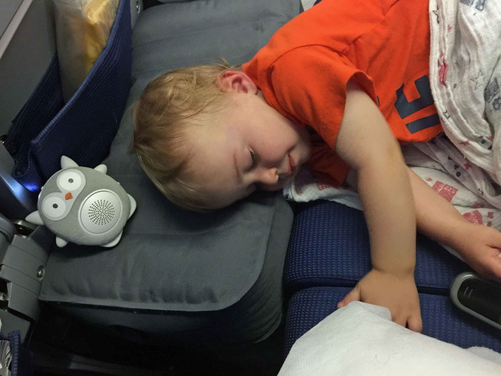 a toddler, from the Baby Can Travel blog, sleeps on a Fly Tot toddler airplane bed on a long haul flight.