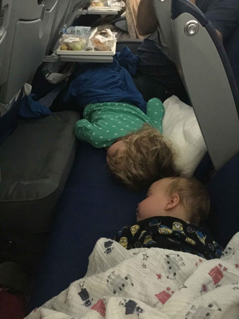 two kids from the BabyCanTravel.com family, sleep soundly on a long haul flight using their Fly Tot inflatable airplane beds.