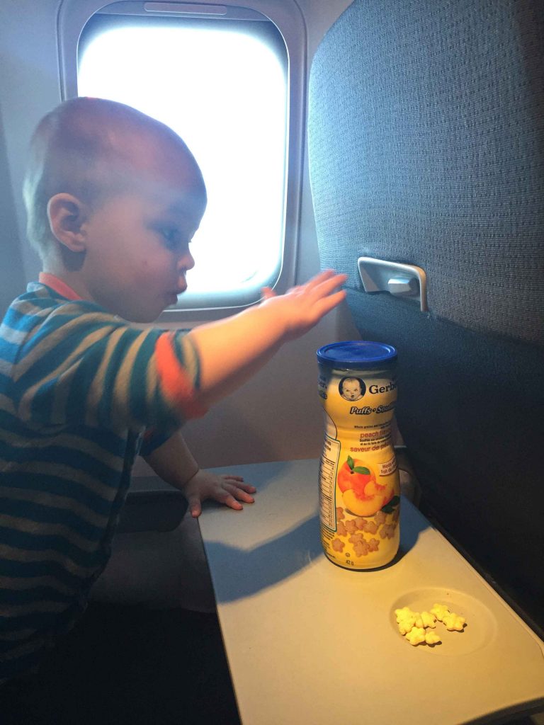 a 1 year old baby from the BabyCanTravel.com family eats Gerber Puffs - providing nourishment and entertainment for a long plane ride.