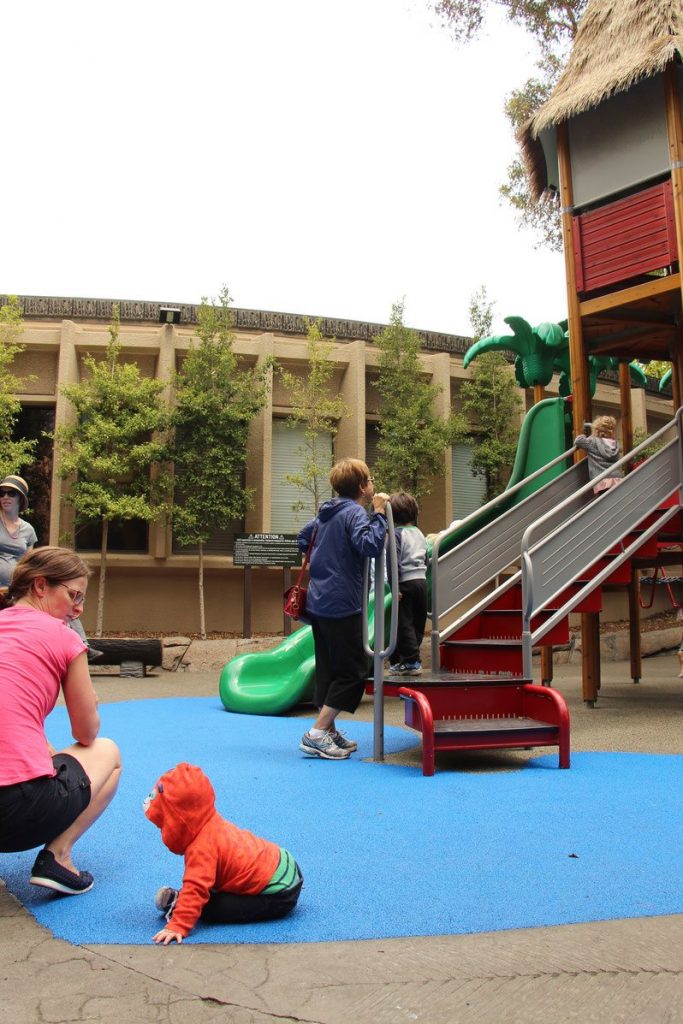 A baby and toddler enjoy a playground at the San Diego Zoo on a family trip to California.