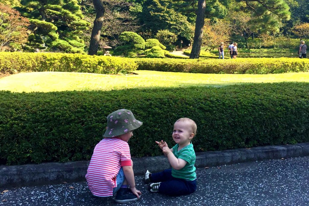 two toddlers play in a beautiful garden on a family trip to Japan