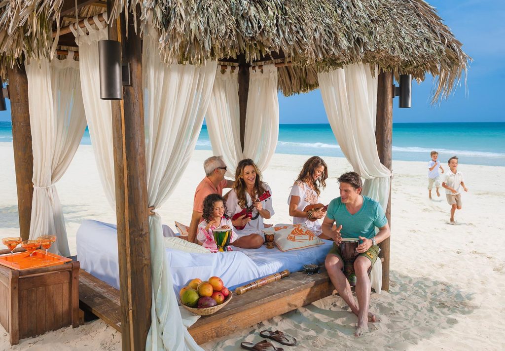 a family enjoys fun in a beachfront cabana at the baby-friendly Beaches Negril Resort & Spa.