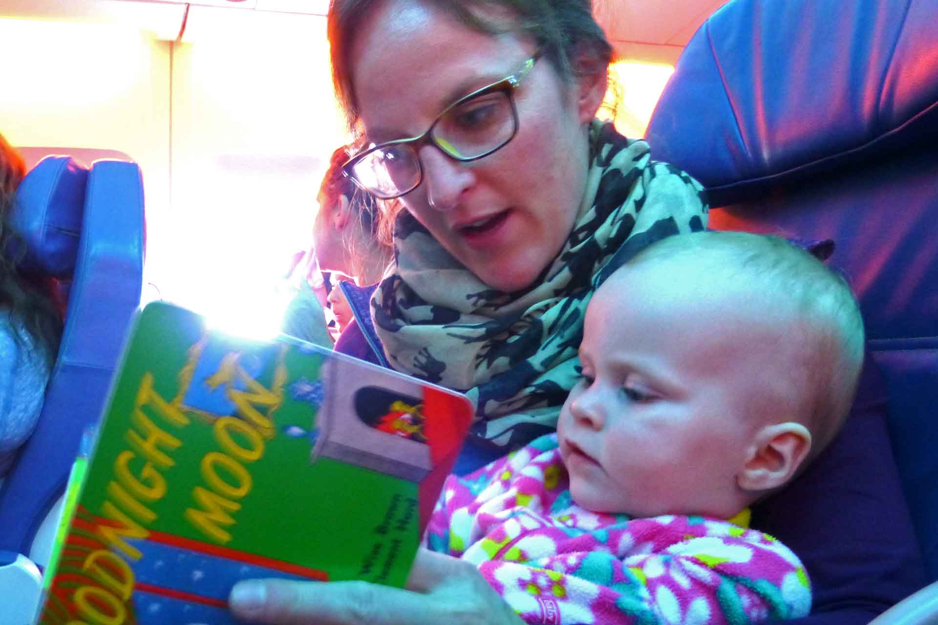 Celine Brewer, of BabyCanTravel.com, reads Goodnight Moon to her infant while on a fight for a family vacation.