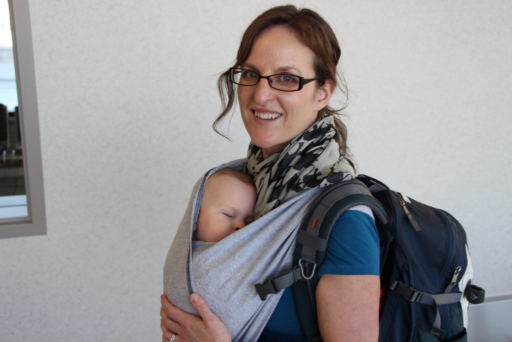 Celine Brewer, of the Baby Can Travel website, carries her newborn in a Baby K'tan wrap at the airport before a family trip.