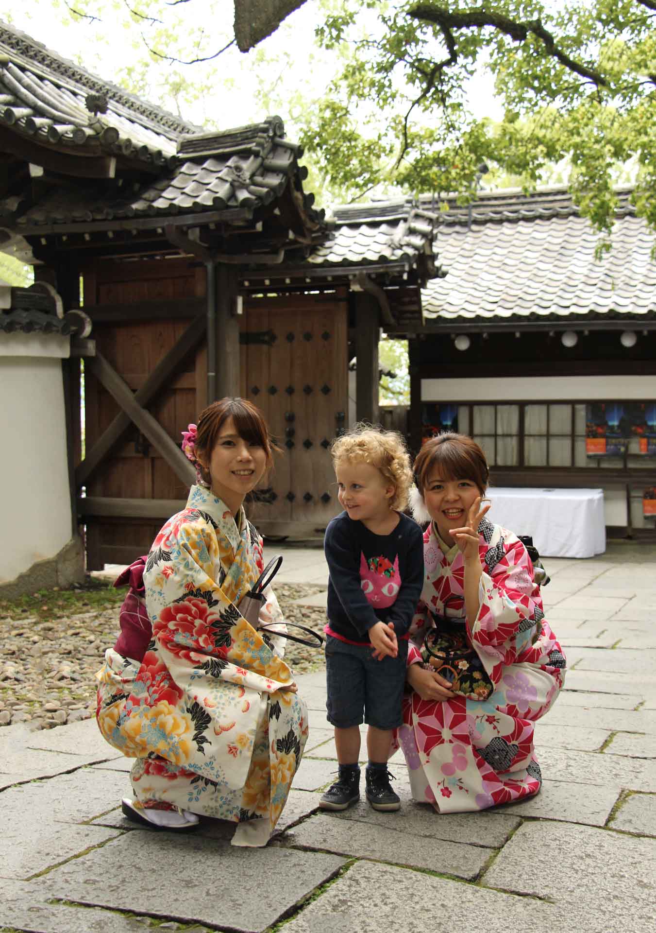 girls dressed like geishas pose for a picture with our toddler at the Shoren-in Temple in Kyoto Japan