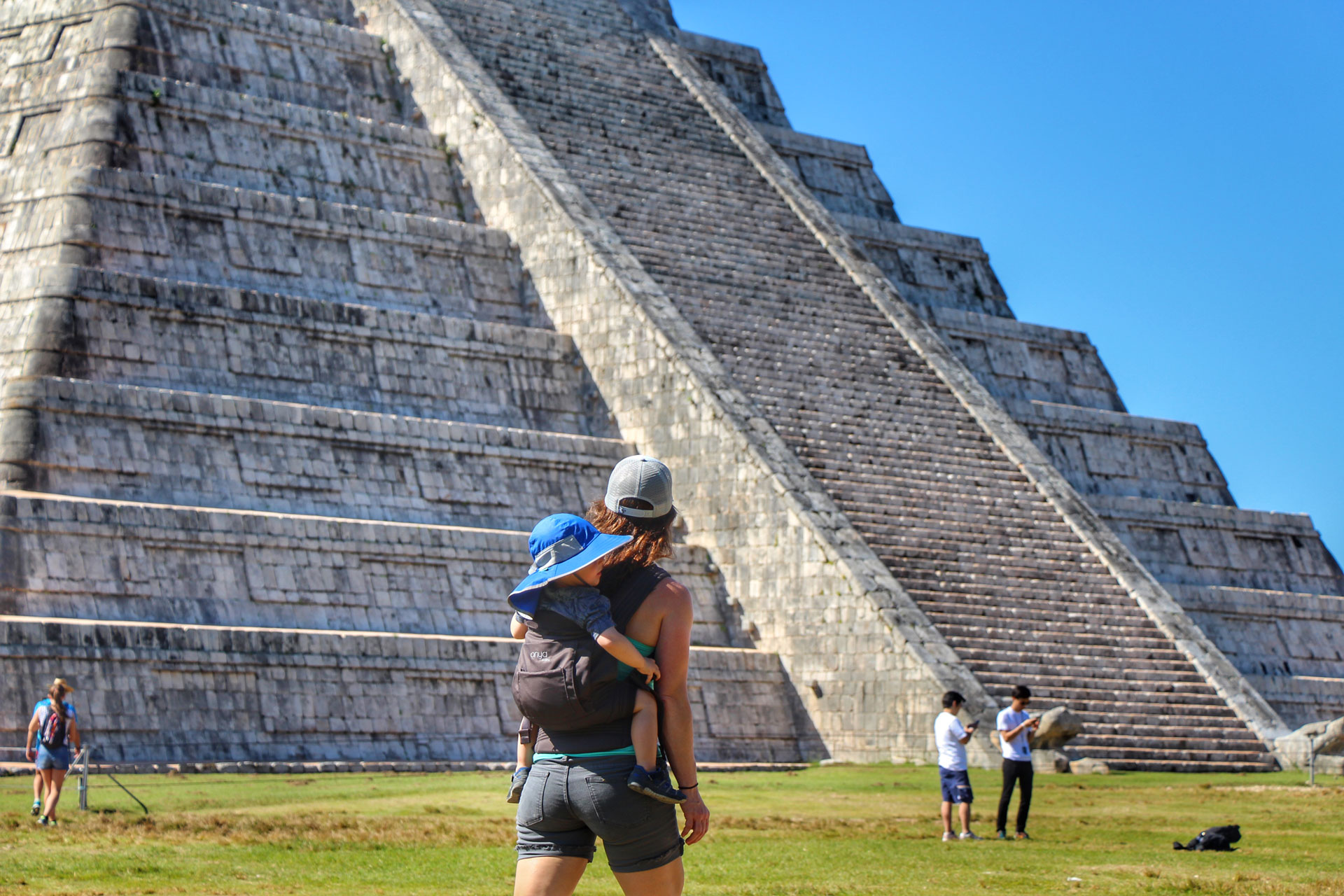 Celine Brewer carries her toddler in an Onya Baby NexStep Carrier while visiting Chichen Itza with her kids.