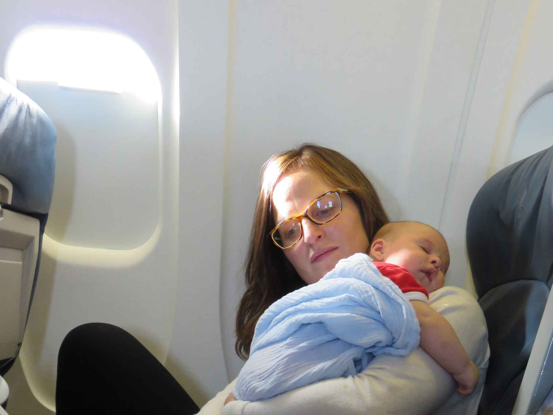 an infant sleeps in his mothers' arms during his very first flight.