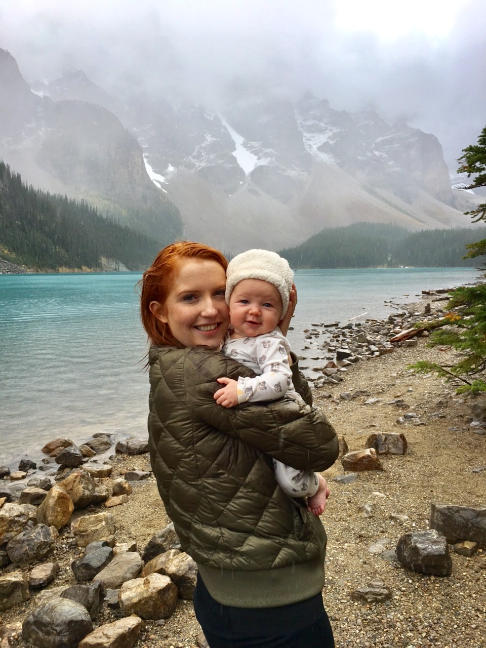 a mother holds her happy baby while on a family trip to the mountains.
