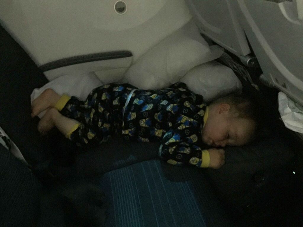 a young child sleeps on an original fly tot inflatable airplane cushion.
