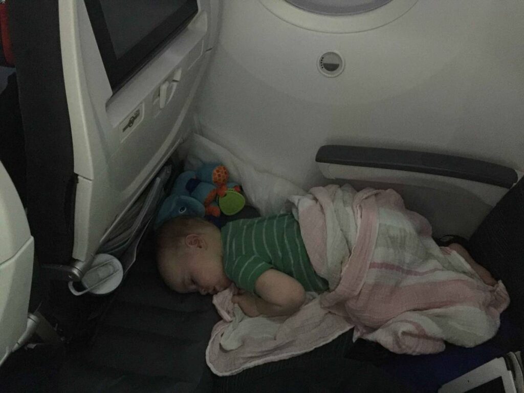 a toddler enjoys sleeping on a plane while using an an inflatable bed for airplane.