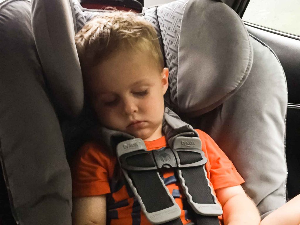 a toddler sleeps during a long car trip on a family vacation.