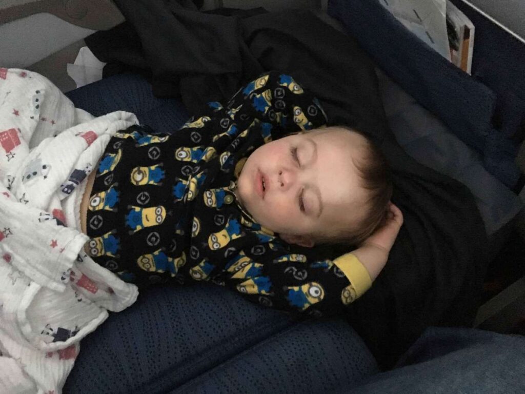 a toddler sleeps comfortably on  the flat space created by his Original Fly tot airplane bed.