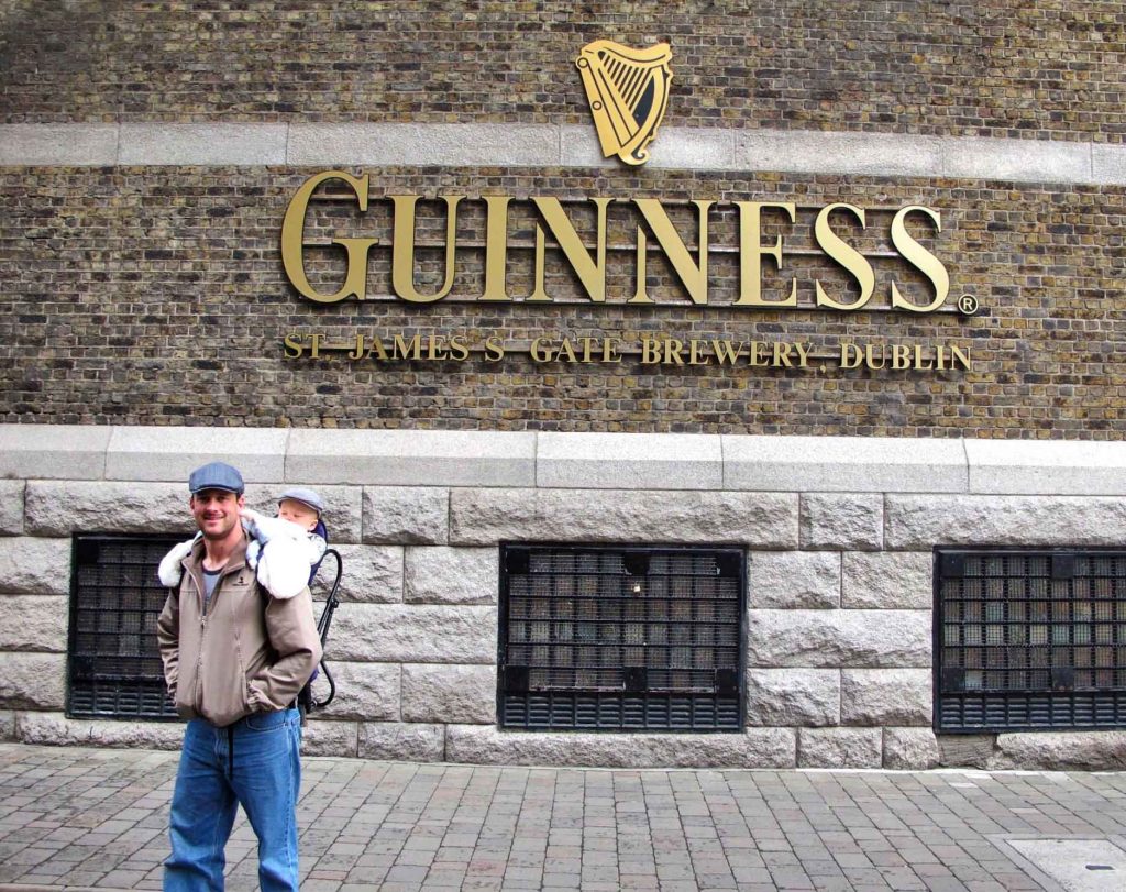 a happy dad carries his baby to the Guinness Brewery on a family vacation to Dublin, Ireland.