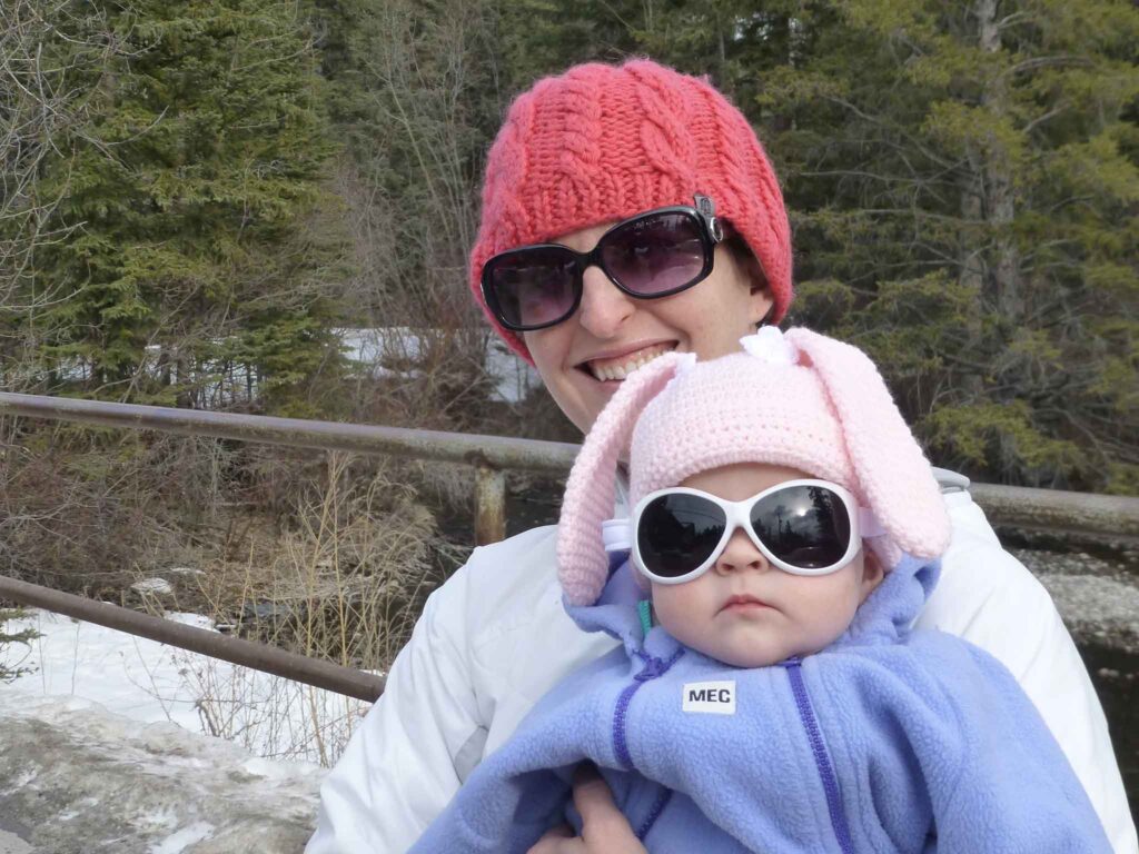 a baby is dressed warmly for winter in a cute pink bunny toque and a fleece bunting suit.