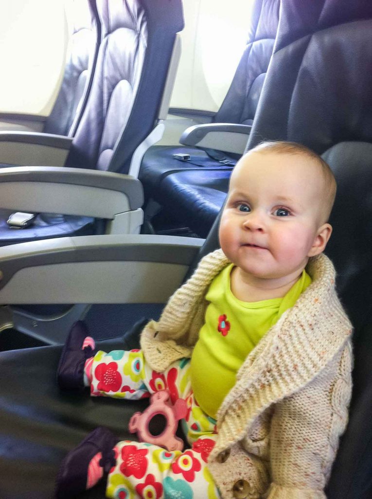 A baby sits on her airline seat waiting for her domestic flight to begin