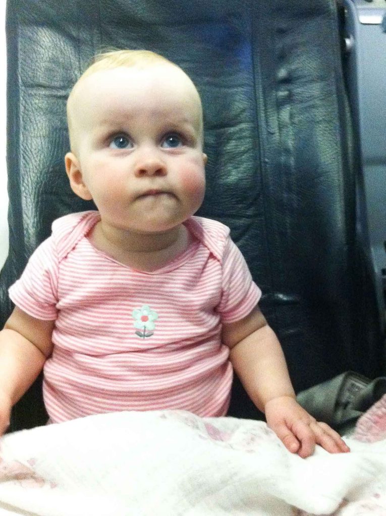 a young child sits calmly in her airplane seat on a domestic flight with her mom