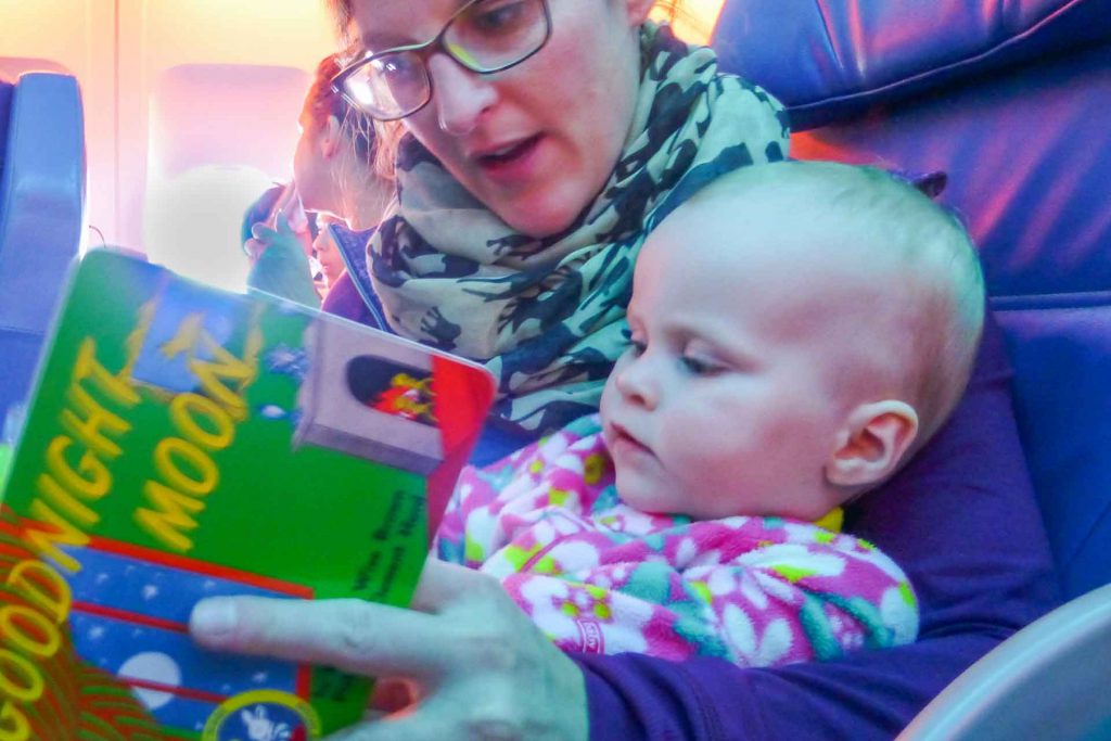 A mother reads Goodnight Moon to her baby to prepare her infant to sleep on the plane