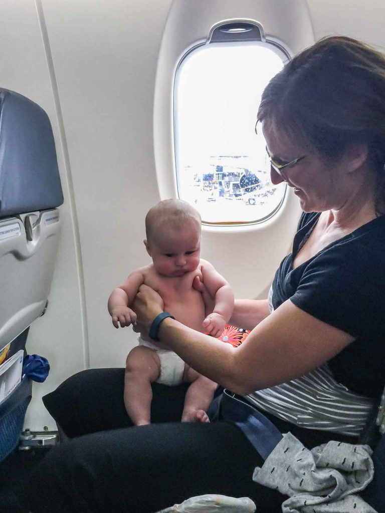 A mom shares her airplane seat with her baby boy to save money while flying with a baby