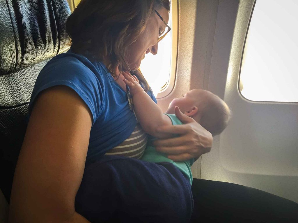 A mom smiles at her lap baby as they share an airline seat