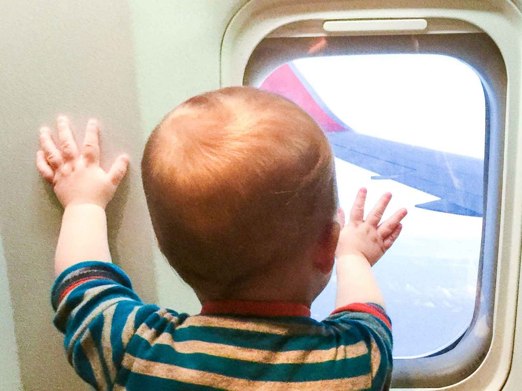 An infant looks out the airplane window