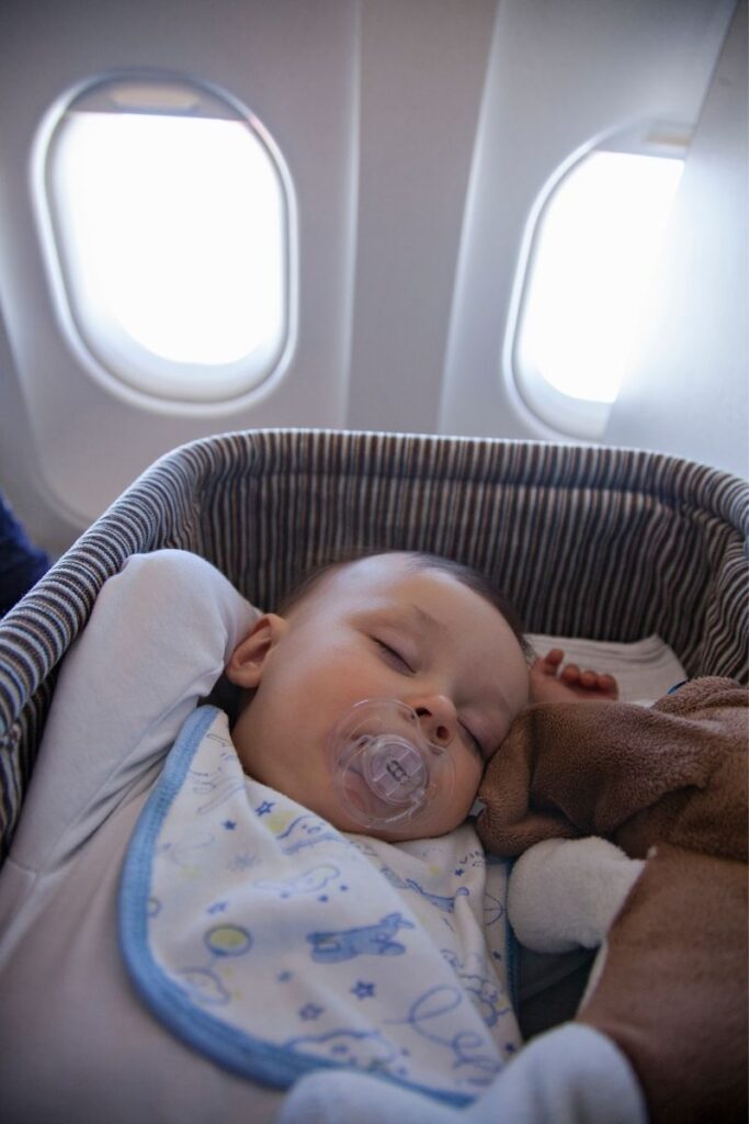 a baby sleeping on plane in an airline bassinet