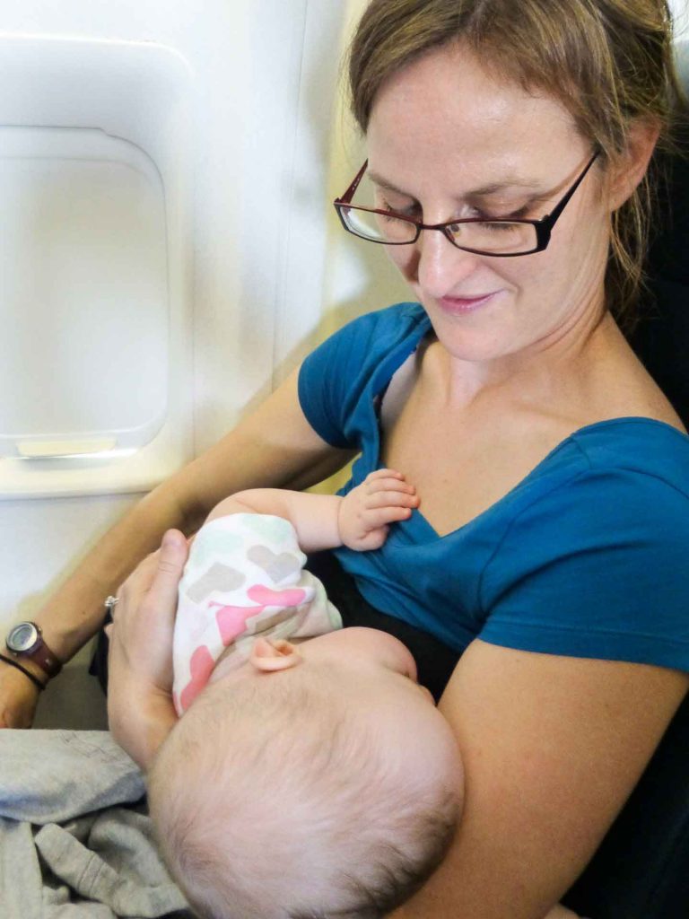 a mother holds her sleeping infant while on a family flight