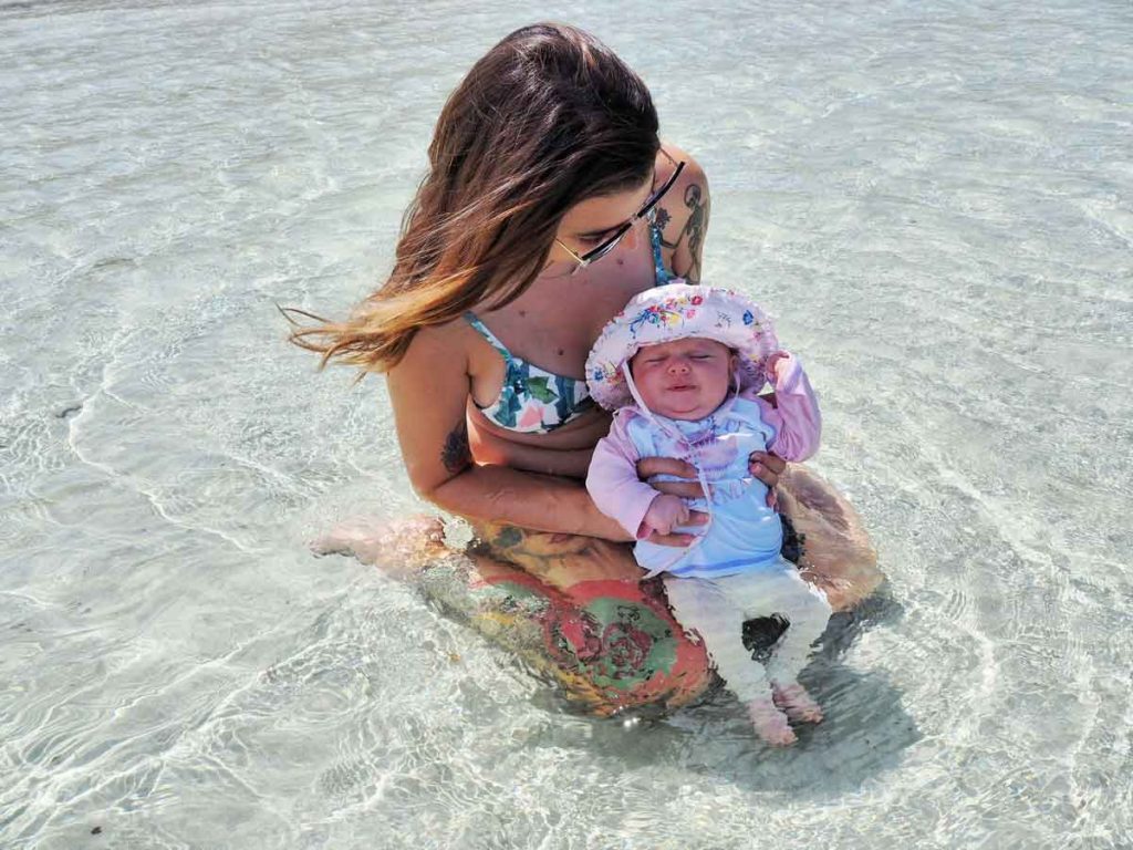 a mother plays with her infant in the water on a family holiday to Bali, Indonesia.
