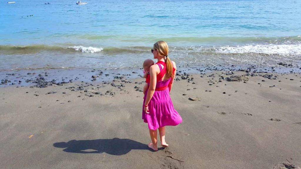 a mother walks along the ocean in Costa Rica with a baby