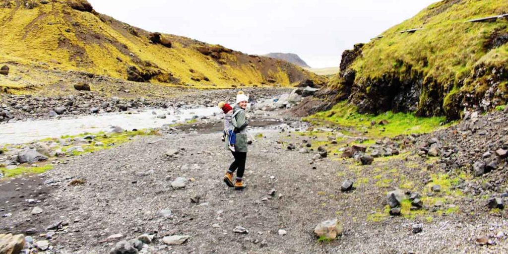 a mother carries her child while on a chilly hike during a family vacation to Iceland with a toddler