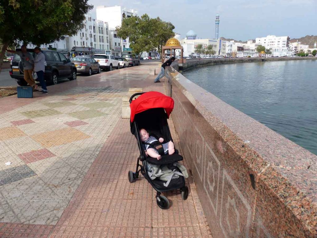 a baby sleeps in a stroller near the water in Oman - one of the best places to travel with baby in the middle east.
