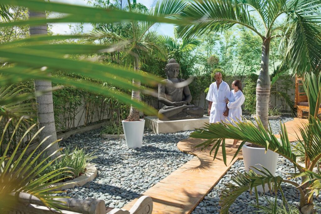 A couple walking through the spa gardens at the baby-friendly Nickelodeon Punta Cana all-inclusive resort