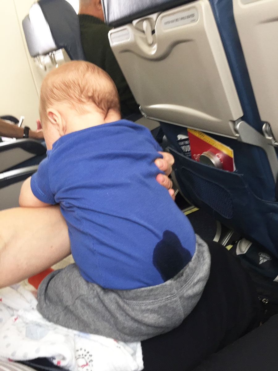 Celine Brewer, owner of BabyCanTravel.com, holds a baby who just pooped through his diapers on a flight.