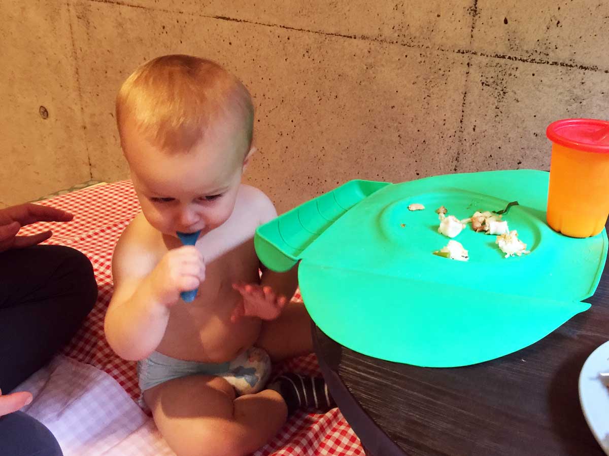 a baby from the BabyCanTravel.com family travel website, eats from a silicone place mat while on a family vacation to Japan.