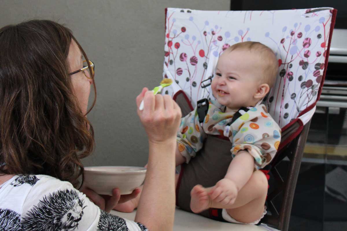 Celine Brewer, from Baby Can Travel, feeds her baby in a hotel room using a portable travel high chair.