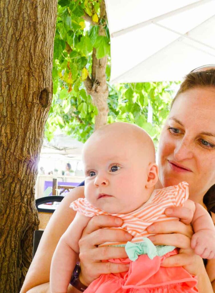 a proud mother holds her 3 month old while traveling in Barcelona with a Baby