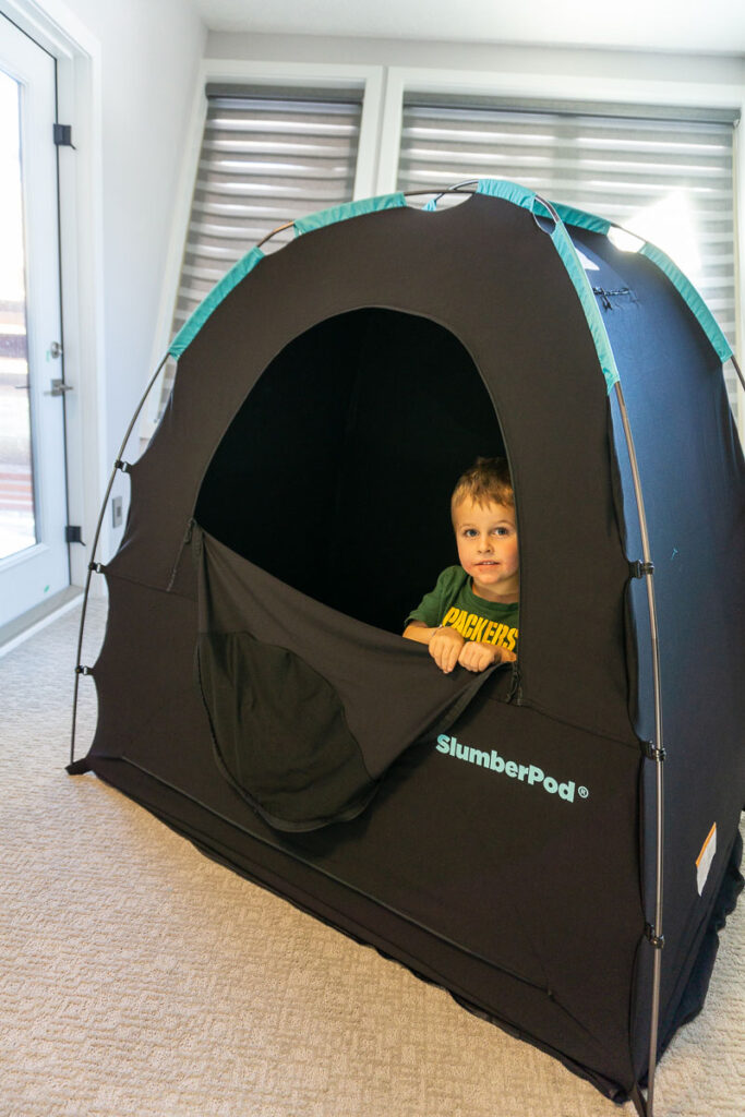 a toddler from the BabyCanTRavel.com family, stands inside his SlumberPod blackout tent.