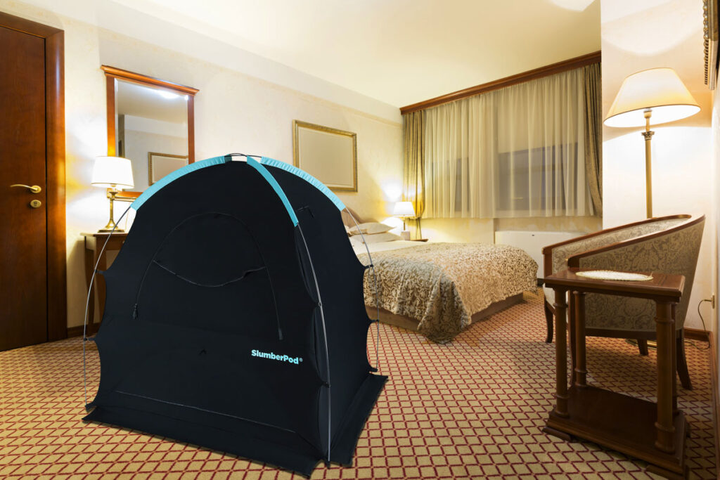 A SlumberPod crib blackout cover set up in a in hotel room.