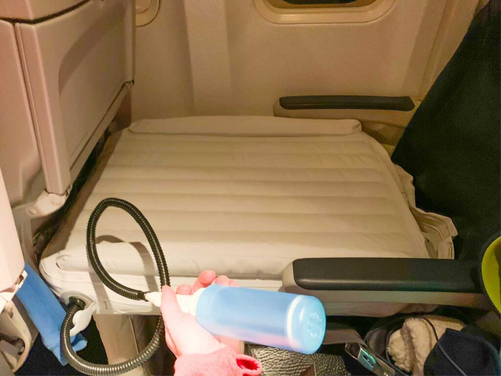 Woman holding pump to inflate Flyaway Designs toddler airplane bed